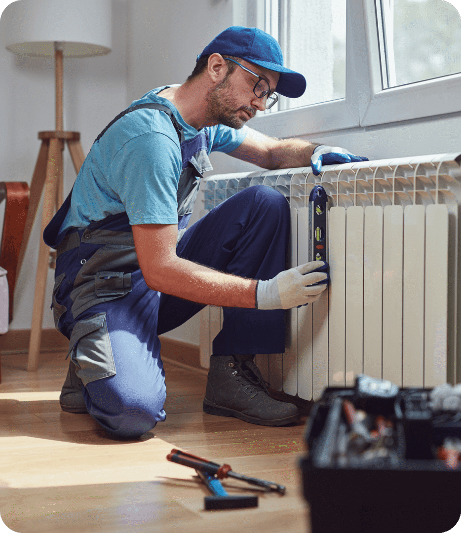 Worker checking radiator with a level tool