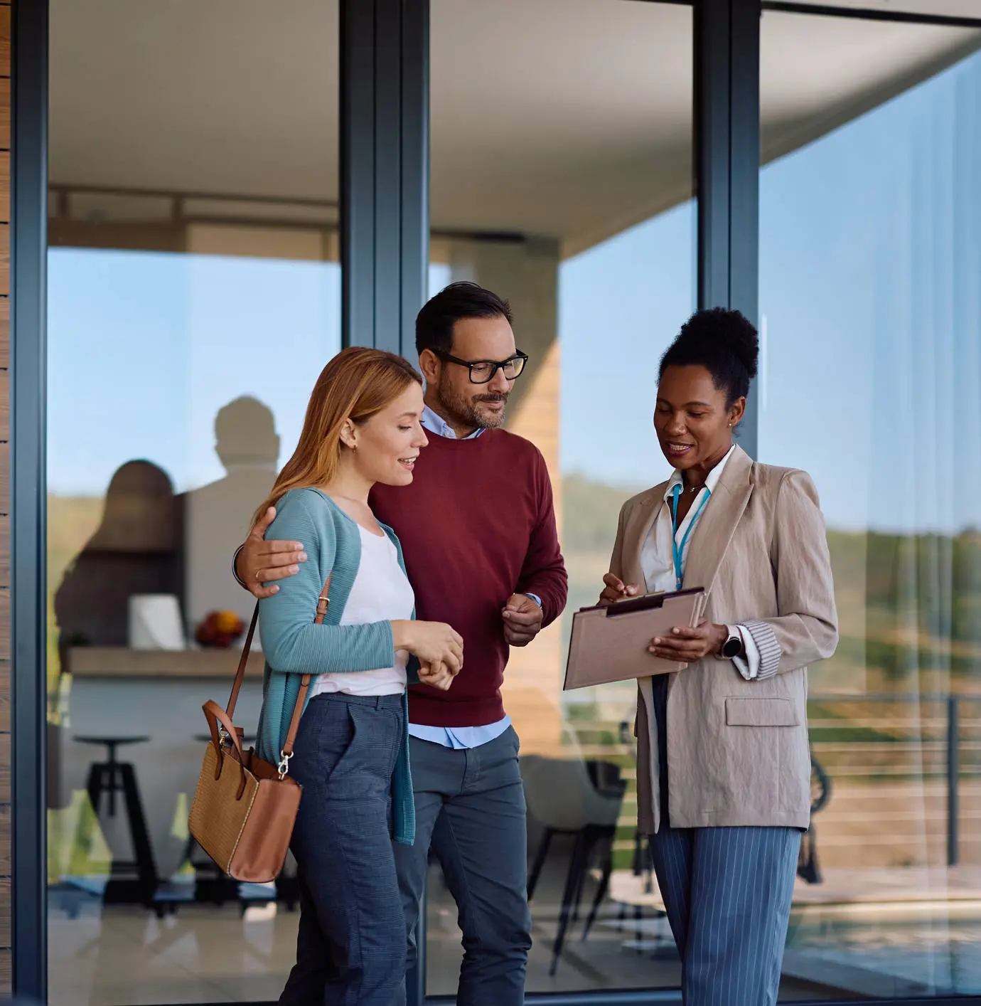 Real estate agent consulting couple outside modern home